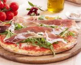 Pyszna pizza prosciutto z rukolą, pomidorami i oliwą z oliwek. Idealna na włoską ucztę.