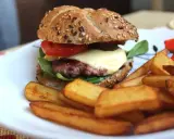 Pyszne, prawdziwe burgery przepis na domowy obiad. Soczysty kotlet, ser, warzywa i chrupiące frytki na talerzu.
