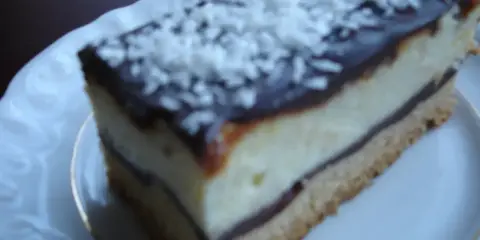 Szybkie ciasto z białym serem i budyniem, polane czekoladą i posypane wiórkami. Idealne na deser.