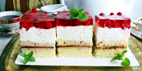 Pyszny biszkopt z serkiem mascarpone i bitą śmietaną, przełożony dżemem, z galaretką truskawkową i malinami.
