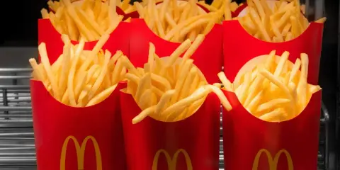 Rzędy czerwonych opakowań z logo McDonald's, wypełnione chrupiącymi frytkami. Zastanawiasz się, ile kosztują małe frytki w McDonald's?