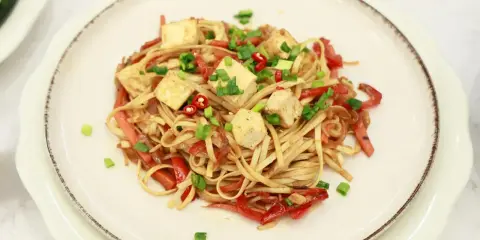 Pyszny makaron z tofu, papryką i szczypiorkiem, posypany chili. Idealne danie dla wegan.