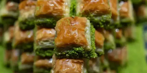 Słodka, złocista baklava, co to za przysmak! Warstwy ciasta filo, orzechów i syropu, posypane zielonymi pistacjami.