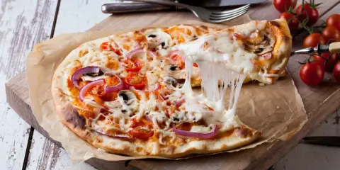 Ciągnący się ser z pizzy 32 cm z pomidorkami i cebulą. Zastanawiasz się, ile kcal ma pizza 32 cm?