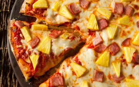 Pyszna pizza z ananasem i szynką, z ciągnącym się serem i chrupiącym ciastem. Idealna na szybki obiad.