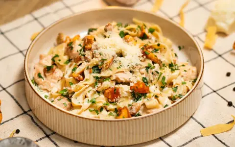 Pyszny makaron w sosie kurkowym z kawałkami kurczaka i posypany parmezanem.