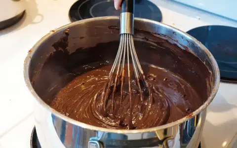 Mieszanie gorącej, płynnej czekolady trzepaczką, kluczowy etap w procesie temperowania czekolady.