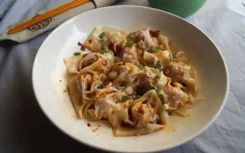 Pyszne pierożki wonton w pikantnym sosie, posypane szczypiorkiem i sezamem. Ciasto do wontonów jest cienkie i delikatne.