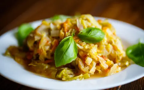 Pyszny bigos z młodej kapusty, duszony z marchewką i przyprawami, udekorowany listkami bazylii. Idealny przepis, jak ugotować dobry bigos z młodej kapusty.