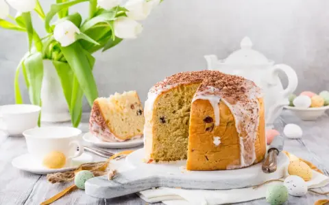 Pyszna babka włoska z lukrem i czekoladową posypką, udekorowana na Wielkanoc z tulipanami i kolorowymi jajeczkami.