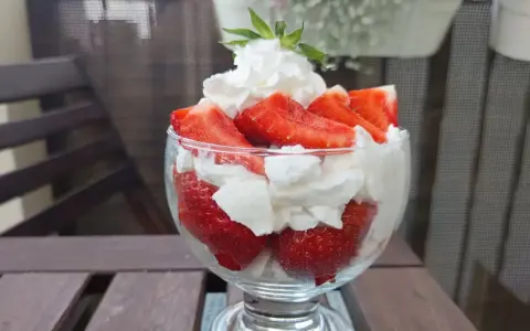 Pyszne, świeże truskawki ze śmietaną w pucharku, gotowe do schrupania.
