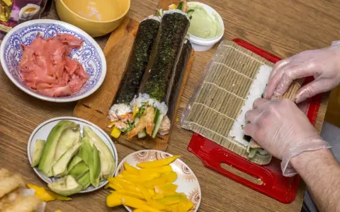 Przygotowanie uramaki: ryż, awokado, mango, krewetki i marynowany imbir czekają na zwinięcie w pyszne rolki sushi.