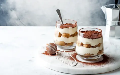 Dwa pucharki z kremowym, warstwowym deserem z biszkoptów i kakao. Idealne na najprostsze tiramisu.