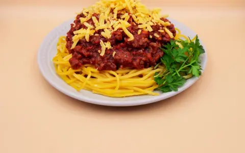 Spaghetti bolognese z tartym serem i natką pietruszki. Prosty przepis na pyszny obiad.