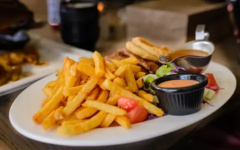 Porcja frytek z sosem i sałatką. Zastanawiasz się, ile kalorii ma porcja frytek?