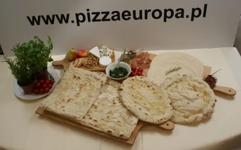 Gotowe ciasto na pizzę, świeże zioła, pomidorki, ser i inne dodatki na drewnianych deskach. Idealne na domowe wypieki.
