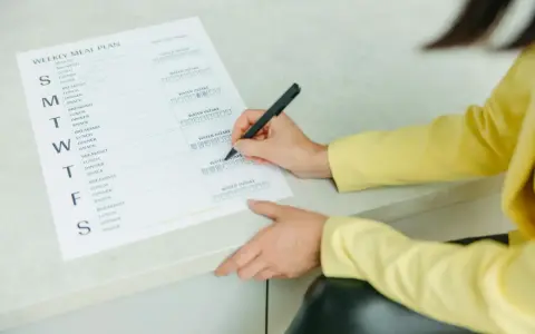 Planowanie posiłków na tydzień, w tym menu na weekendowe grillowanie. Kobieta zaznacza wypite szklanki wody.