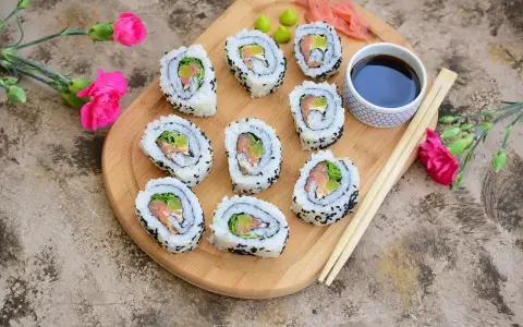 California sushi z łososiem i awokado, posypane czarnym sezamem, podane z sosem sojowym i wasabi.