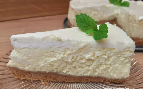 Pyszny sernik ze śmietaną kremówką, udekorowany listkiem mięty, na kruchym spodzie.