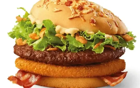 Apetyczny burger drwala z chrupiącym plackiem cebulowym, soczystą wołowiną, chrupiącym boczkiem i świeżą sałatą.