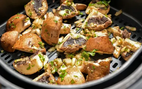 Pyszne pieczarki z airfryer, przyprawione i posypane natką pietruszki, gotowe do podania.
