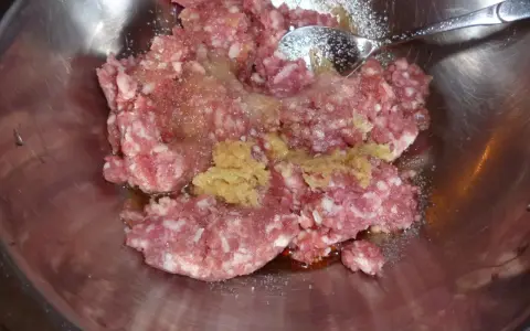 Mielone mięso z dodatkami, gotowe do przygotowania soboro. W metalowej misce znajduje się surowe mięso mielone, przyprawy i sos.