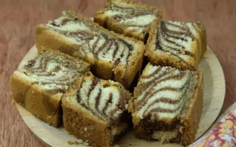 Puszyste ciasto zebra przepis. Pokrojone kawałki ciasta z charakterystycznym wzorem zebry ułożone na drewnianej desce.