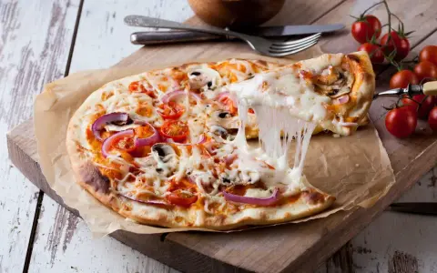 Ciągnący się ser z pizzy 32 cm z pomidorkami i cebulą. Zastanawiasz się, ile kcal ma pizza 32 cm?