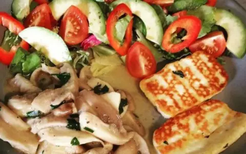 Pyszne halloumi z grilla podane z sałatką z awokado, pomidorów i papryki.