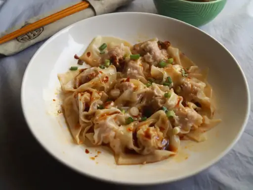 Pyszne pierożki wonton w pikantnym sosie, posypane szczypiorkiem i sezamem. Ciasto do wontonów jest cienkie i delikatne.