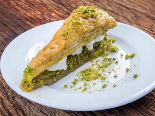 Pyszna baklawa z pistacjami i kremem na białym talerzu. Idealny przepis na deser.