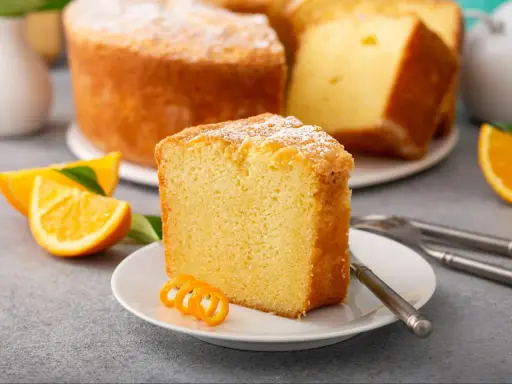 Puszysta babka cytrynowa, oprószona cukrem pudrem, z plasterkami pomarańczy. Idealna na niedzielne popołudnie, gdy szukasz przepisu na babkę wiszącą.