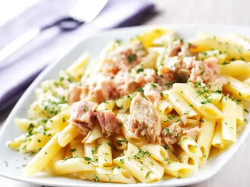 Penne z tuńczykiem w sosie własnym, posypane natką pietruszki. Proste i pyszne danie.