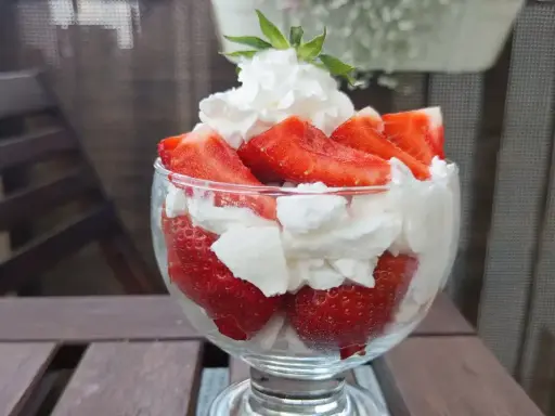 Pyszne, świeże truskawki ze śmietaną w pucharku, gotowe do schrupania.