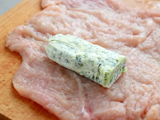 Rolada z kurczaka na desce, z masłem ziołowym w środku. Przygotowanie do zawinięcia devolaj.
