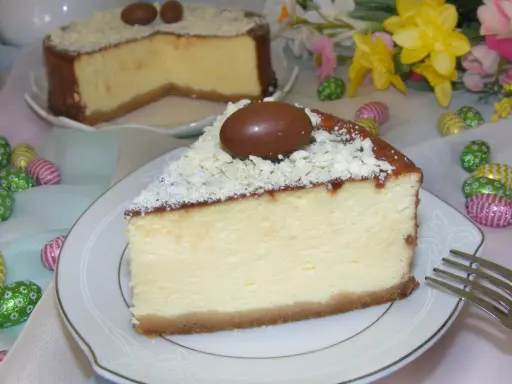Wspaniały sernik z mascarpone, udekorowany czekoladowymi jajeczkami i wiórkami białej czekolady, idealny na Wielkanoc.