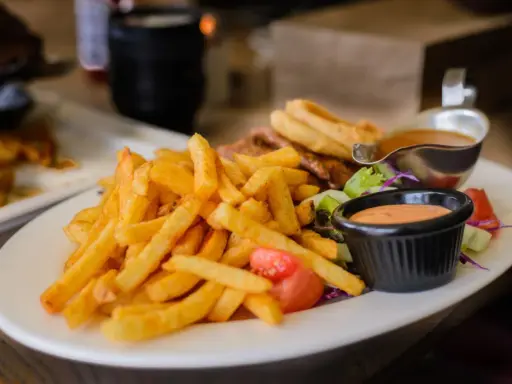 Porcja frytek z sosem i sałatką. Zastanawiasz się, ile kalorii ma porcja frytek?