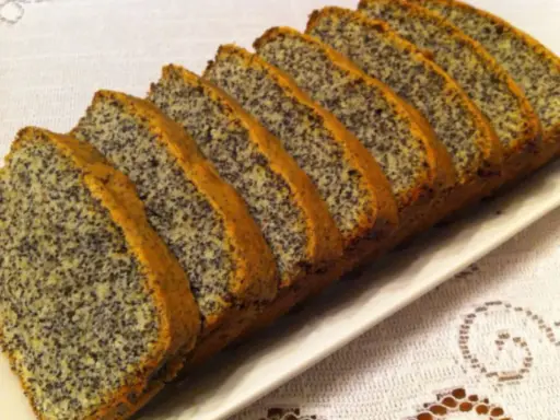Pokrojony w plastry, pyszny piegusek ciasto z makiem, ułożony na białej paterze.