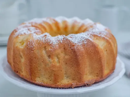 Puszysta babka cytrynowa na oleju Ewy Wachowicz, oprószona cukrem pudrem, prezentuje się apetycznie na białej paterze.
