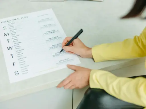 Planowanie posiłków na tydzień, w tym menu na weekendowe grillowanie. Kobieta zaznacza wypite szklanki wody.