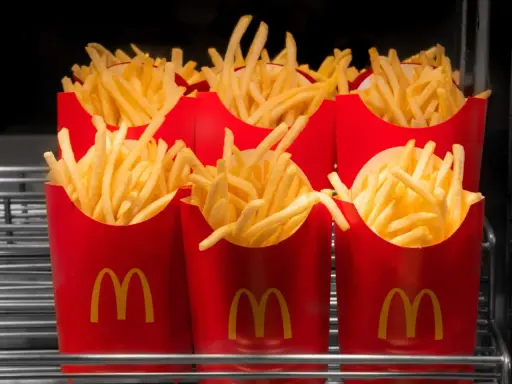 Rzędy czerwonych opakowań z logo McDonald's, wypełnione chrupiącymi frytkami. Zastanawiasz się, ile kosztują małe frytki w McDonald's?