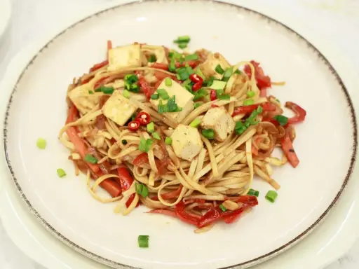 Pyszny makaron z tofu, papryką i szczypiorkiem, posypany chili. Idealne danie dla wegan.