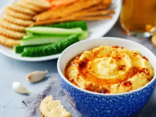 Pyszny, kremowy hummus, idealny jako sos do frytek, podany z chrupiącymi krakersami i świeżymi warzywami.