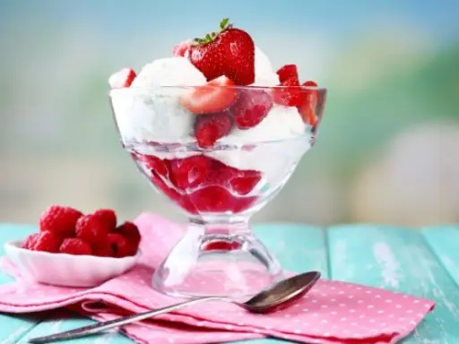 Pyszne lody nuii z malinami i truskawkami w pucharku.