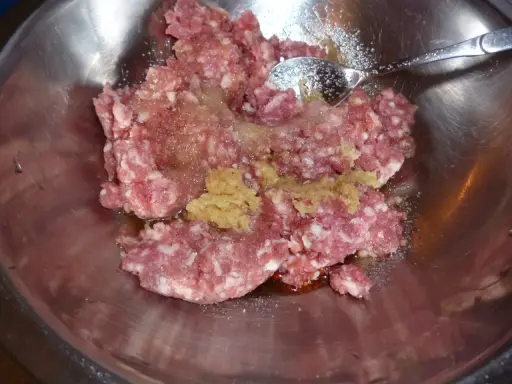 Mielone mięso z dodatkami, gotowe do przygotowania soboro. W metalowej misce znajduje się surowe mięso mielone, przyprawy i sos.