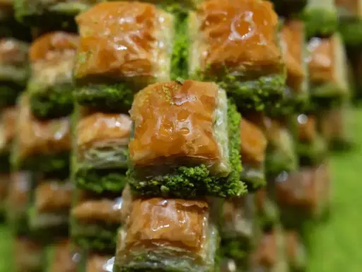 Słodka, złocista baklava, co to za przysmak! Warstwy ciasta filo, orzechów i syropu, posypane zielonymi pistacjami.