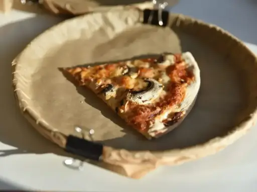 Kawałek pizzy z pieczarkami na papierowym talerzu. Zastanawiasz się, ile kalorii ma średnia pizza?
