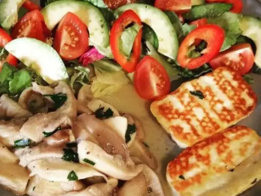 Pyszne halloumi z grilla podane z sałatką z awokado, pomidorów i papryki.