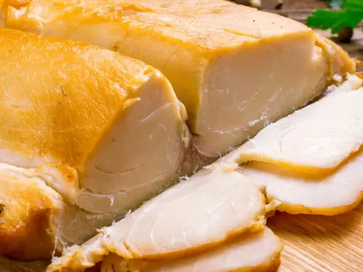 Dwa kawałki wędzonej ryby maślanej, jeden pokrojony w plastry, leżą na desce.