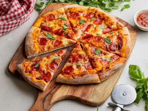 Pyszna pizza pepperoni z ciągnącym się serem i świeżą bazylią, gotowa do podania.